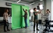 © Arts Eira - Media production team collaborating to set up a professional green screen studio with lighting equipment