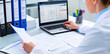 © mustafiz - Researcher working on laptop in medical office managing clinical data files and reports organized in binders with researcher laboratory administration biotechnology analysis pharmaceutical