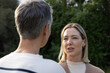 © wavebreak3 - Female friends talking in garden, speaker wearing ribbed top and earrings, listener with gray hair