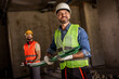 © Mediteraneo - Two builders holding small green pipes on an industrial renovation site.