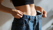 © photo for everything - Fit female body show weight loss success in oversized blue jeans, healthy diet, and fitness journey reveal, waistline transformation in golden hour light