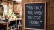 © Emre Akkoyun - Chalkboard displaying motivational quote you only fail when you stop trying in a blurred woodworking workshop