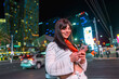 © unai - Woman tourist using smartphone on modern las vegas street at night