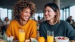© Glitchmint - Two smiling women enjoying breakfast together at a cafe with orange juice and fruit
