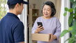 © Phonlasit - Pharmacy Delivery Worker Giving Medicine Package to Elderly Woman at Home