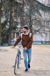 © Oscar - Young man walking with bicycle in urban park