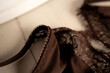 © Yaraslava - close-up of brown lace lingerie with delicate scalloped trim draped over a wooden hanger, bathed in warm soft light intimate textured fabric details captured with shallow depth of field, organic
