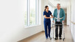© OlgaNeuroArt - Physiotherapist helping elderly patient walk with a walker in hospital corridor. Senior man in rehabilitation after surgery. Physical therapy and recovery concept