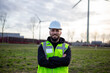 © Martin - Electrical technician standing confidently at clean energy site with wind turbines, focusing on sustainable power industry
