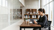 © Tania Zbrodko - Female university student studying on a tablet in a bright modern library, representing digital education and academic focus.
