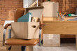 © Pixel-Shot - Chair with cardboard box in office on moving day