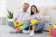 © New Africa - Spring cleaning. Happy couple with detergents sitting on floor at home