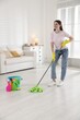 © New Africa - Spring cleaning. Happy woman tidying up floor with mop at home