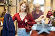 © JackF - Young European woman holds a stylish dark blue coat in a clothing store. Shopping for outerwear in the shopping center