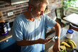 © Geber86 - Active mature man checking smartwatch while prepping smoothie in home kitchen