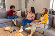 © wavebreak3 - Diverse female friends laughing, talking and holding red drinks on gray sectional sofa with chips