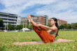 © leungchopan - Healthy woman practicing navasana boat yoga pose on park grass