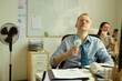 © DragonImages - Caucasian middle aged businessman cooling himself with handheld fan at desk during office heat, showing summer workplace discomfort. Useful for burnout, productivity, heatwave campaigns