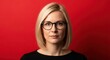 © Aku - Portrait of a young blonde woman with glasses on a vibrant red background.