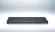 © Aji - Black smartphone isolated on a light gray studio background.