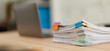© David - Stack of document files, paperwork, and reports organized with binder clips on a desk next to a blurred laptop, representing business management and data organization