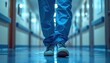 © Zulfadhli - Close-up view of a medical professional's legs and feet wearing blue scrubs and comfortable shoes while walking down a hospital corridor.