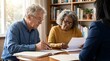 © Hassan - Elderly couple sitting at a wooden table reviewing important legal documents with their professional financial advisor
