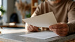 © forenna - College application rejection letter on a kitchen counter, parent's hand visible gripping the edge, teenager's school backpack visible in the blurred background, the single material detail in a dome