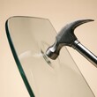 © ANRI - Metal hammer striking tempered safety glass sheet demonstrating impact resistance