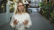 © Krakenimages.com - Woman in white shirt with red glasses holds hands forward stop gesture on narrow street; personal boundary caution.