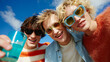 © twc - Three cheerful young men with stylish sunglasses and vibrant attire share a joyful moment under a bright blue sky, holding a refreshing drink