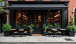 © Viktor - New York cafe facade with outdoor seating. Black awning over glass windows and doors shows shelves stocked with items. Small tables and chairs outside on sidewalk.