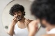 © Prostock-studio - Focused Young Male With Curly Hair Flossing Teeth In Front Of Mirror At Home Bathroom, Taking Care Of Oral Hygiene. Smiling And Engaged In Daily Routine Of Dental Care. Healthcare Concept.