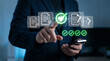 © ParinApril - Businessman verifying digital documents with green checkmarks hologram on smartphone