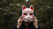 © GANBA - 両手で狐のお面を顔に当てる人物