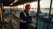 © Suska - A Construction Foreman Reviewing Plans On-Site Near a Busy Port at Dusk