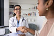 © fizkes - Cheerful middle aged physician shaking hands with young Black patient, giving respect, support, confidence, empathy. Healthy young African woman givin handshake to doctor, thanking for medical help