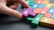 © Wankatsu - Hand placing purple wooden block with human icon into a colorful puzzle for team building and human resources recruitment business lifestyle concept