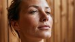 © AZ Studio - Close-up of a woman's flushed face glistening with sweat in a warm wooden sauna