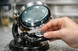© Fotograf - A person holds a magnifying glass over a table, examining an object