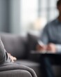 © Firadoaw - male patient sitting on sofa talking with psychologist during therapy session in cozy clinic office, mental health counseling concept, therapist listening and taking notes, soft natural light