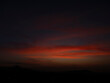 © Arturo Revueltas - Oscuro cielo de crepúsculo con nubes rojas intensas y silueta de montañas en el horizonte