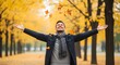 © Mourad - Man enjoys the autumn season while standing in a park with golden yellow leaves falling around him.