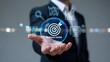 © Faheem - Businessman presenting a business model concept with a target and various strategy icons floating above his hand in a futuristic setting
