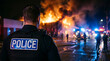© Pupun - Rear view of a police officer in tactical gear monitoring a catastrophic building fire at night with emergency vehicles and first responders present