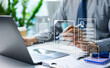 © Father_Studio - Businessman reviewing digital insurance policies and compliance documents on laptop and tablet. Risk management data security policy protection, regulatory compliance and insurance technology concept.