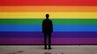 © miss irine - Person stands before rainbow flag mural. Symbolizes pride, equality, and LGBTQ community support. Colorful background represents diversity and unity.