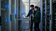 © chonchon - Two IT professionals collaborating on server maintenance in data center using laptop
