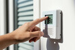 © Lubov - Hand adjusts digital thermostat setting lower for energy saving. Person controls indoor temperature reducing home heating costs for better economy. Adjusting warmth efficiency for winter.