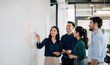 © oeisdesign - Business team discussing strategy on whiteboard.